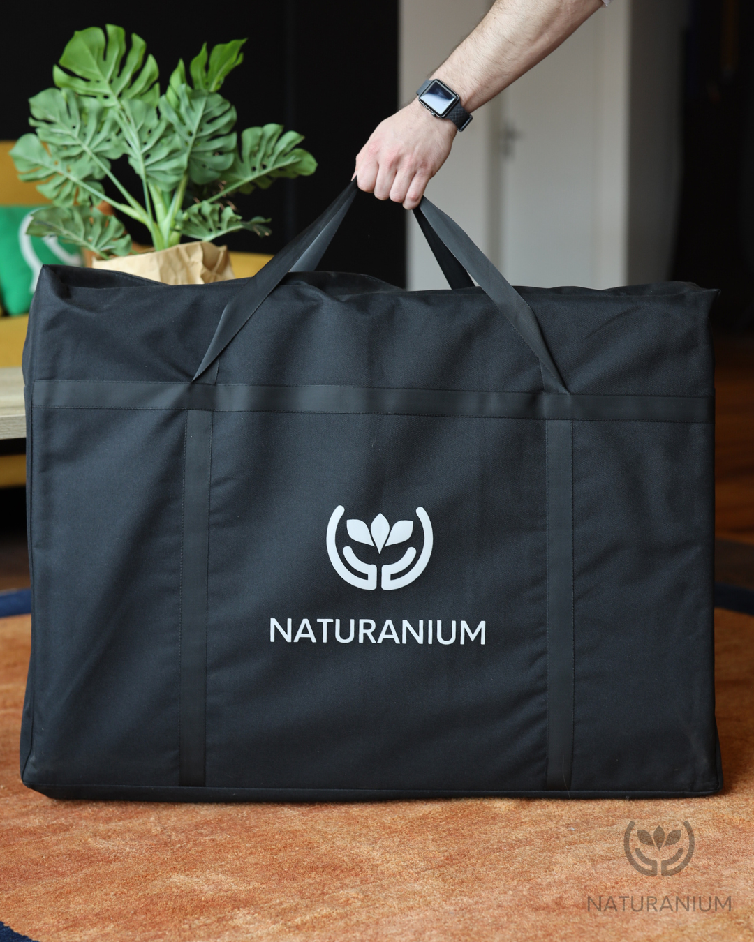 Hand trägt die Naturanium Kristallmatte in einer praktischen Tragetasche für leichten Transport.